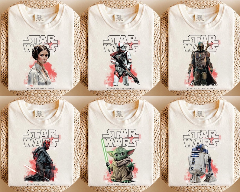 May include: Six cream-colored t-shirts featuring Star Wars characters and the text "STAR WARS" in a bold font. Each shirt displays a different character illustration with the text "ATTACK OF THE CLONES". The shirts are arranged on woven mats.