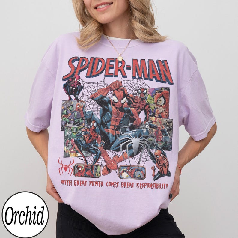 May include: A light purple Spider-Man t-shirt featuring a comic book style design with Spider-Man in various action poses, spiderwebs, and the text "SPIDER-MAN" and "WITH GREAT POWER COMES GREAT RESPONSIBILITY".