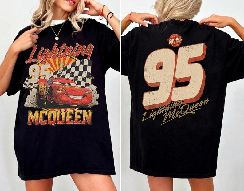 May include: A black t-shirt featuring a graphic of the red race car Lightning McQueen with the number 95, a checkered flag, and the text Lightning McQueen on the front. The back displays the large number 95 and the text Lightning McQueen.