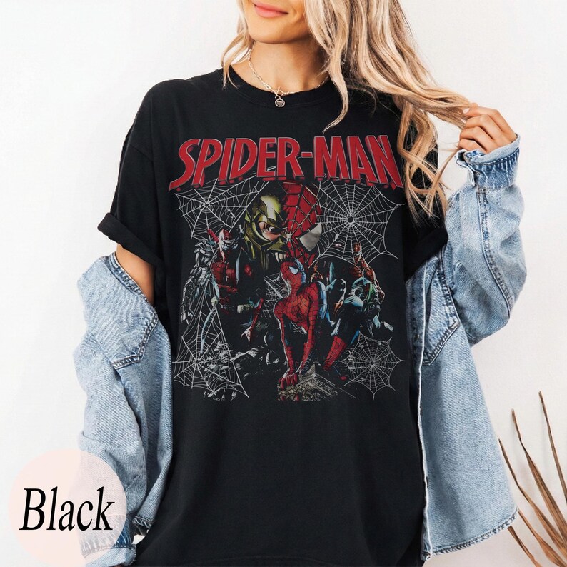 Pu&ograve; includere: T-shirt nera con la scritta rossa "SPIDER-MAN" e una grafica di Spider-Man e altri personaggi, su sfondo a ragnatela. La parola "Black" &egrave; stampata in basso.