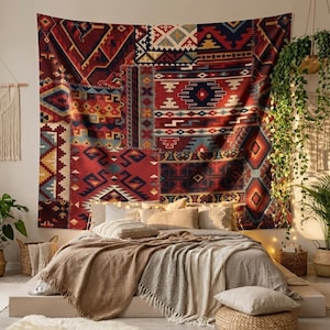 Puede incluir: Un gran tapiz de retazos en tonos rojos, azules y crema cuelga sobre una cama. El tapiz presenta patrones geométricos y una variedad de texturas. La cama está cubierta con ropa de cama y mantas de tonos neutros, creando un ambiente acogedor en el dormitorio.