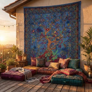 Puede incluir: Un área de descanso al aire libre de estilo bohemio con un gran tapiz azul con un diseño de árbol. El área de descanso incluye cojines y almohadas coloridas en tonos de rojo, naranja y verde azulado. La escena está ambientada en una terraza de madera con plantas en macetas y luces de cadena.
