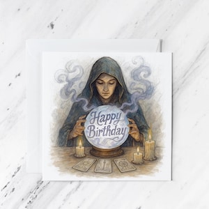May include: A birthday card featuring a watercolor illustration of a hooded figure gazing into a crystal ball with the words "Happy Birthday." The scene includes lit candles and tarot cards, with wisps of smoke rising from the crystal ball.