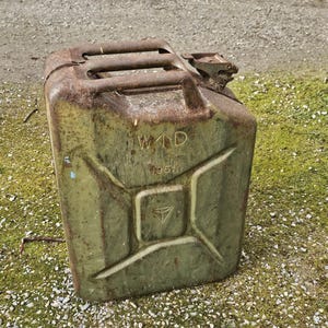 May include: An aged olive green metal fuel canister, showing signs of rust. The rectangular container features a handle and a spout. The text "W1D 1951" is printed on the front.