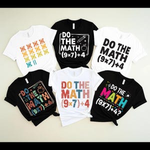 Può includere: Collezione di magliette bianche e nere con grafiche a tema matematico. I disegni includono la frase "Do the Math" con equazioni e simboli, e grafiche colorate di matite e mele. Le magliette sono a maniche corte.