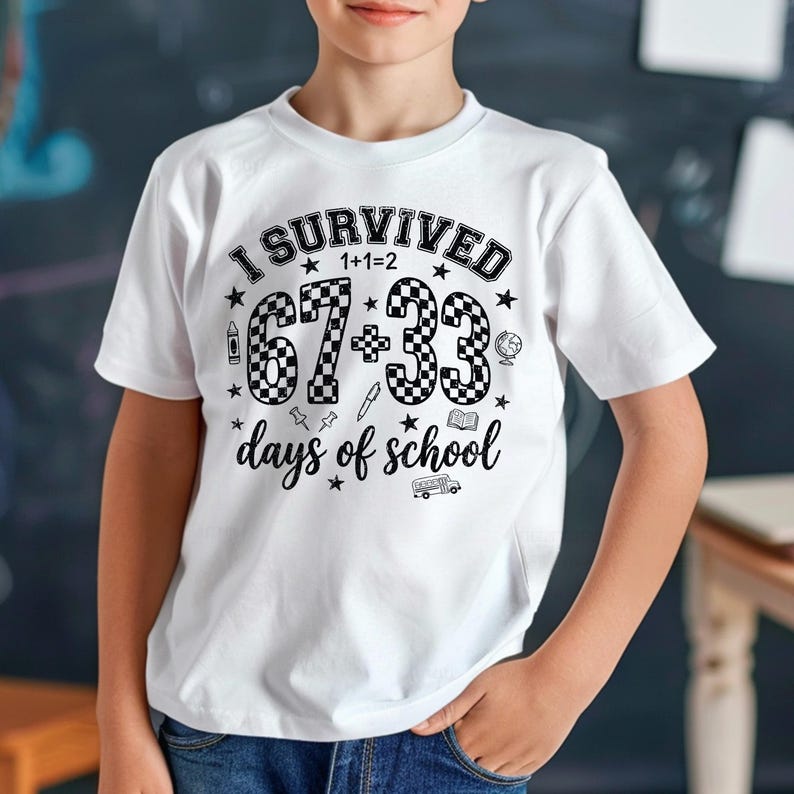 以下が含まれることがあります： 「I SURVIVED 1+1=2 67+33 days of school」の黒い文字が入った白いTシャツ。67と33の数字は市松模様です。シャツには、学校用品と星の小さなイラストも付いています。