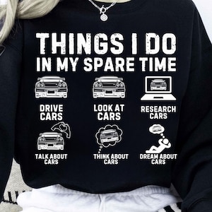 May include: Black sweatshirt with white text and car graphics. The text reads "THINGS I DO IN MY SPARE TIME" with illustrations of cars and related activities: drive, look at, research, talk about, think about, and dream about cars.
