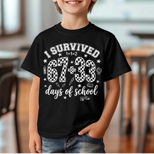 以下が含まれることがあります： 「I SURVIVED 1+1=2 67+33 days of school」の白文字がプリントされた黒いTシャツ。67と33の数字は市松模様。Tシャツはクルーネックで半袖です。