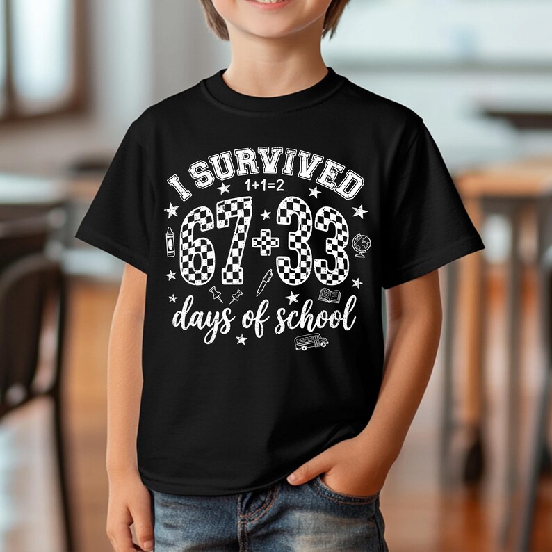 以下が含まれることがあります： 黒いTシャツに、白い文字で「I SURVIVED 1+1=2 67+33 days of school」と書かれています。数字の67と33は市松模様です。鉛筆、地球儀、本など、学校をテーマにしたグラフィックが描かれています。
