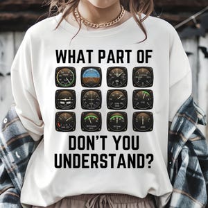 Puede incluir: Camiseta blanca con el texto "WHAT PART OF DON'T YOU UNDERSTAND?" sobre una cuadrícula de doce instrumentos de aviación. Los indicadores muestran información como la velocidad y la altitud.