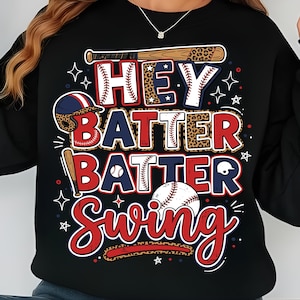 May include: Black sweatshirt with a baseball-themed graphic. The design features the words "HEY BATTER BATTER SWING" in red, white, and blue, with baseballs, bats, and stars. The letters have a baseball stitch design.