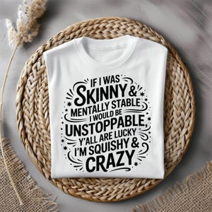May include: White t-shirt with a black graphic design. The text reads: "IF I WAS SKINNY & MENTALLY STABLE I WOULD BE UNSTOPPABLE, Y'ALL ARE LUCKY I'M SQUISHY & CRAZY."