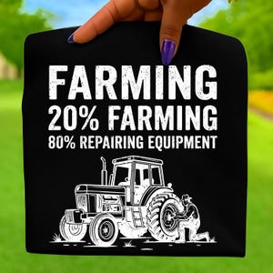 Puede incluir: Camiseta negra con texto blanco: "FARMING 20% FARMING 80% REPAIRING EQUIPMENT". Una ilustración blanca de un tractor y una persona reparando un neumático está debajo del texto. La camiseta está sujeta por una mano con esmalte de uñas morado.
