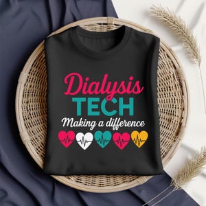 Puede incluir: Camiseta negra de cuello redondo con las palabras "Dialysis TECH Making a difference" en rosa, turquesa y blanco. Debajo, cinco corazones coloridos con líneas de frecuencia cardíaca.