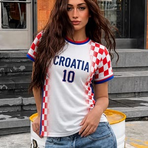 May include: White Croatia soccer jersey with red and white checkered pattern on the sleeves and shoulders. The jersey has blue trim and the word "CROATIA" and the number "10" in blue.