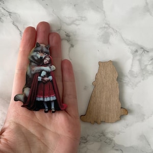 A wolf hugging red riding hood, wooden cutout for crafting and jewellery making.