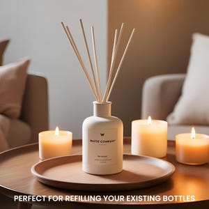 May include: A white ceramic reed diffuser with wooden reeds, branded "White Company". The diffuser is on a wooden tray with three lit candles. The text at the bottom reads "PERFECT FOR REFILLING YOUR EXISTING BOTTLES."