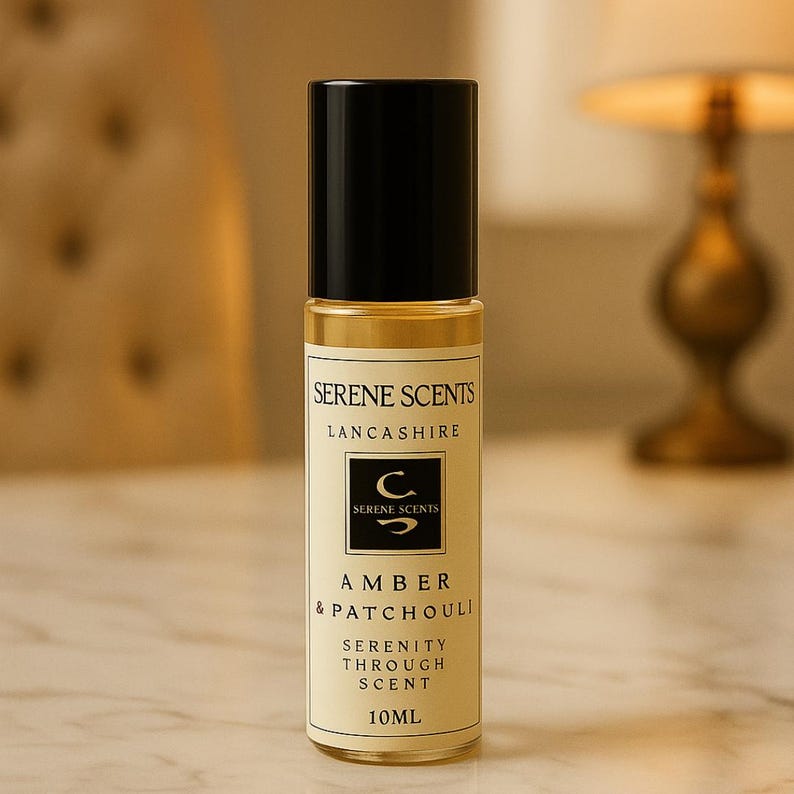 May include: A roll-on perfume bottle with a black cap and a clear glass body. The label reads "Serene Scents Lancashire" and "Amber & Patchouli". The bottle contains 10ml of perfume.