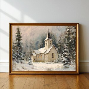 May include: A framed painting depicts a snow-covered church with a tall steeple, surrounded by snow-laden evergreen trees. The artwork is set in a winter landscape, with a golden frame. The painting evokes a serene, wintry scene.