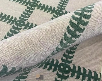 May include: A rolled-up, light-colored rug with a green plaid pattern. The rug has a textured surface and a visible logo that reads "ENGLISH HOME RUG". The green pattern is made up of a series of connected, rectangular shapes.