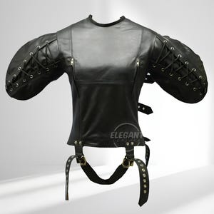 Op de afbeelding: Zwart leren top met aangehechte mouwen, met vetersluiting op de mouwen en een ritssluiting. De top heeft verstelbare bandjes met metalen gespen en een ronde halslijn. Het product is van Elegant Leather.
