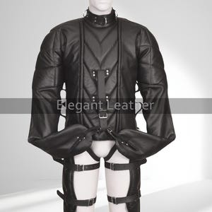 Puede incluir: Chaqueta de cuero negro con diseño acolchado, cuello alto y múltiples correas con hebillas. Las mangas son largas y terminan en un puño. El texto "Elegant Leather" es visible.