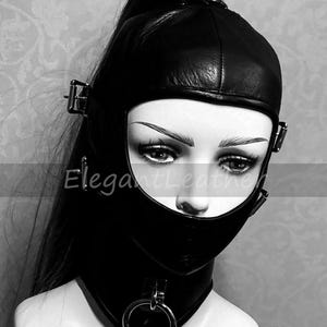 May include: Black leather hood with a face opening, secured with buckles and a neck collar with a metal ring. The text "ElegantLeather" is visible on the hood. The hood is designed to cover the head and neck.