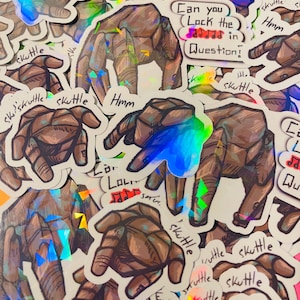 May include: A collection of holographic stickers featuring brown, multi-faceted hand illustrations. Some stickers include the handwritten text "skuttle", "Hmm", or "Can you Lock the notes in Question!" with musical symbols in red.