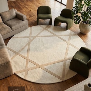 Peut inclure: Un grand tapis circulaire présentant une base de couleur crème avec un motif géométrique de lignes beige entrecroisées formant des triangles et un polygone central. Le tapis est posé sur un plancher en bois dans une pièce avec des meubles.