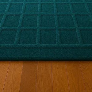 Hand-tufted teal wool carpet with bold square grid design, adding a pop of sophisticated color to a modern home, paired with mid-century style armchairs and brass floor lamps.