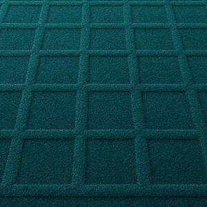 Modern geometric wool rug in deep teal with a textured grid pattern, styled in a luxurious, well-lit room with large arched windows, soft curtains, and polished wooden floors.