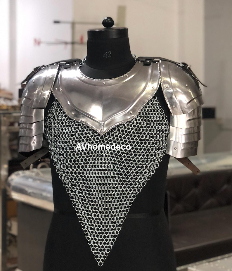 May include: A polished steel chest and shoulder armor set. The armor features layered shoulder plates, a central breastplate, and a chainmail lower section. The armor is displayed on a black mannequin. The text "AVhomedeco" is visible.