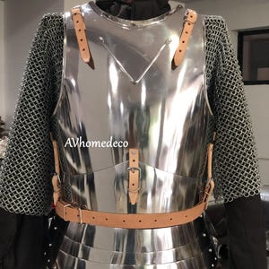 May include: A polished steel breastplate with leather straps and a brown belt. The armor is paired with chainmail sleeves and a black undergarment. The breastplate has a reflective surface and is designed to protect the torso.