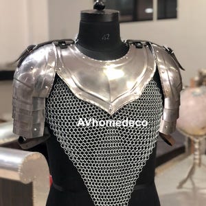 May include: A silver-colored medieval armor breastplate and shoulder guards with chainmail. The armor is displayed on a black mannequin. The text "AVhomedeco" is visible on the chainmail.