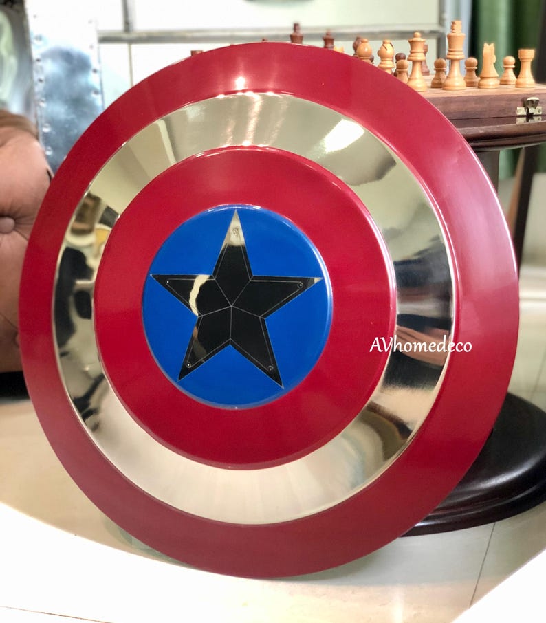 K&ouml;nnte beinhalten: Ein roter, silberner und blauer Schild mit einem schwarzen Stern in der Mitte. Der Schild hat ein kreisf&ouml;rmiges Design mit einem roten Au&szlig;enring, einem silbernen Mittelring und einer blauen Mitte. Der Text "AVhomedeco" ist unten rechts sichtbar.