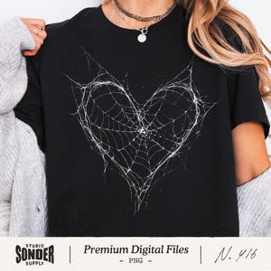 May include: Black t-shirt featuring a white heart-shaped spiderweb design. The shirt has a crew neck and short sleeves. The image also includes the text "Premium Digital Files - PNG - N. 416" and the Studio Sonder Supply logo.