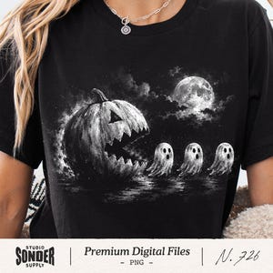 May include: A black t-shirt featuring a white graphic print of a large jack-o'-lantern with a jagged mouth chasing three small ghosts under a full moon. The design has a textured, sketch-like appearance set against the dark fabric of the shirt.