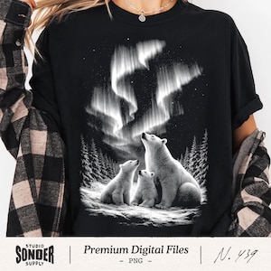 May include: Black t-shirt with a graphic of a polar bear family observing the aurora borealis. The design shows a mother bear and two cubs in a snowy landscape with pine trees. The text "Premium Digital Files" is also visible.