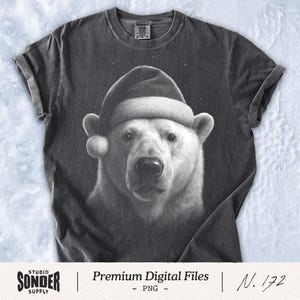 May include: A dark grey t-shirt with a detailed grayscale image of a polar bear wearing a Santa hat. The bear's fur is white, and the hat has a white brim and pom-pom. The shirt has rolled-up sleeves and the text "Premium Digital Files" and "N. 172".