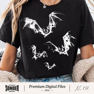 May include: Black t-shirt with a white bat design. The graphic shows several bats with spread wings, giving a spooky and artistic look. This casual wear item is suitable for Halloween or gothic-themed occasions. The shirt is made of a soft material.