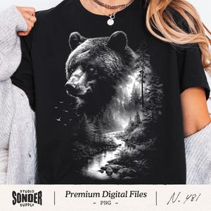 Può includere: T-shirt nero con un'illustrazione in bianco e nero della testa di un orso, con una foresta e un fiume sullo sfondo. La maglietta ha il testo "Premium Digital Files" e "N. 481".