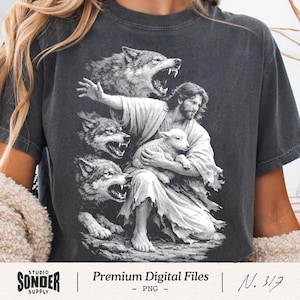 Op de afbeelding: Een antracietgrijs t-shirt met een witte grafische print van een bebaarde figuur in gewaden die een klein lammetje vasthoudt, omringd door drie grommende wolven. Het ontwerp is uitgevoerd in een gedetailleerde, schetsachtige stijl en toont het contrast tussen de kalme figuur en de agressieve wolven op de donkere stof.