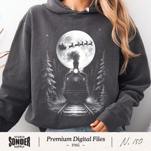 May include: Dark gray hoodie featuring a black and white graphic of a train on tracks, with a full moon, Santa's sleigh, and reindeer. The text "Premium Digital Files" is below the image.
