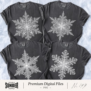 May include: Four charcoal gray t-shirts with white snowflake designs. The snowflakes are detailed and symmetrical. The shirts have rolled-up sleeves. The bottom of the image has the text "STUDIO SONDER SUPPLY | Premium Digital Files - PNG - N. 147."