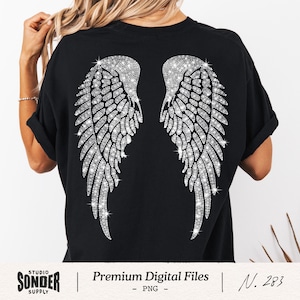 Op de afbeelding: Zwart T-shirt met een sprankelend, met strass bezet engelenvleugelontwerp op de rug. De vleugels zijn gedetailleerd met individuele veren en glitter. Het shirt heeft opgerolde mouwen. De tekst "Premium Digital Files" is onderaan zichtbaar.