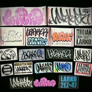May include: A collection of twenty-one rectangular and circular stickers featuring various graffiti-style tags, bubble letters, and block text. Designs include the names LARKO, LARKER, and REKER TROJAN LARKO in black, pink, orange, and blue ink on white paper.