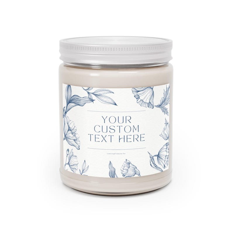 Puede incluir: Un tarro de vela beige con tapa blanca. El tarro tiene una etiqueta con ilustraciones florales azules y el texto "YOUR CUSTOM TEXT HERE". La vela es un art&iacute;culo decorativo.