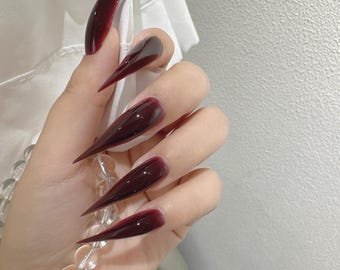 Uñas postizas largas estilo gótico vampiro con efecto stiletto burdeos