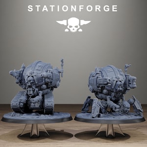 Può includere: Due macchine da guerra in miniatura in resina grigia con il testo STATIONFORGE e un logo a forma di teschio sopra. L'unità a sinistra ha cingoli da carro armato, mentre quella a destra poggia su gambe meccaniche. Entrambi hanno corpi sferici.