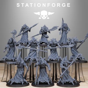 May include: A group of grey miniature figurines, each representing a robed character with different weapons and mechanical components. The figures are displayed on a tiered platform. The text "STATIONFORGE" is visible.